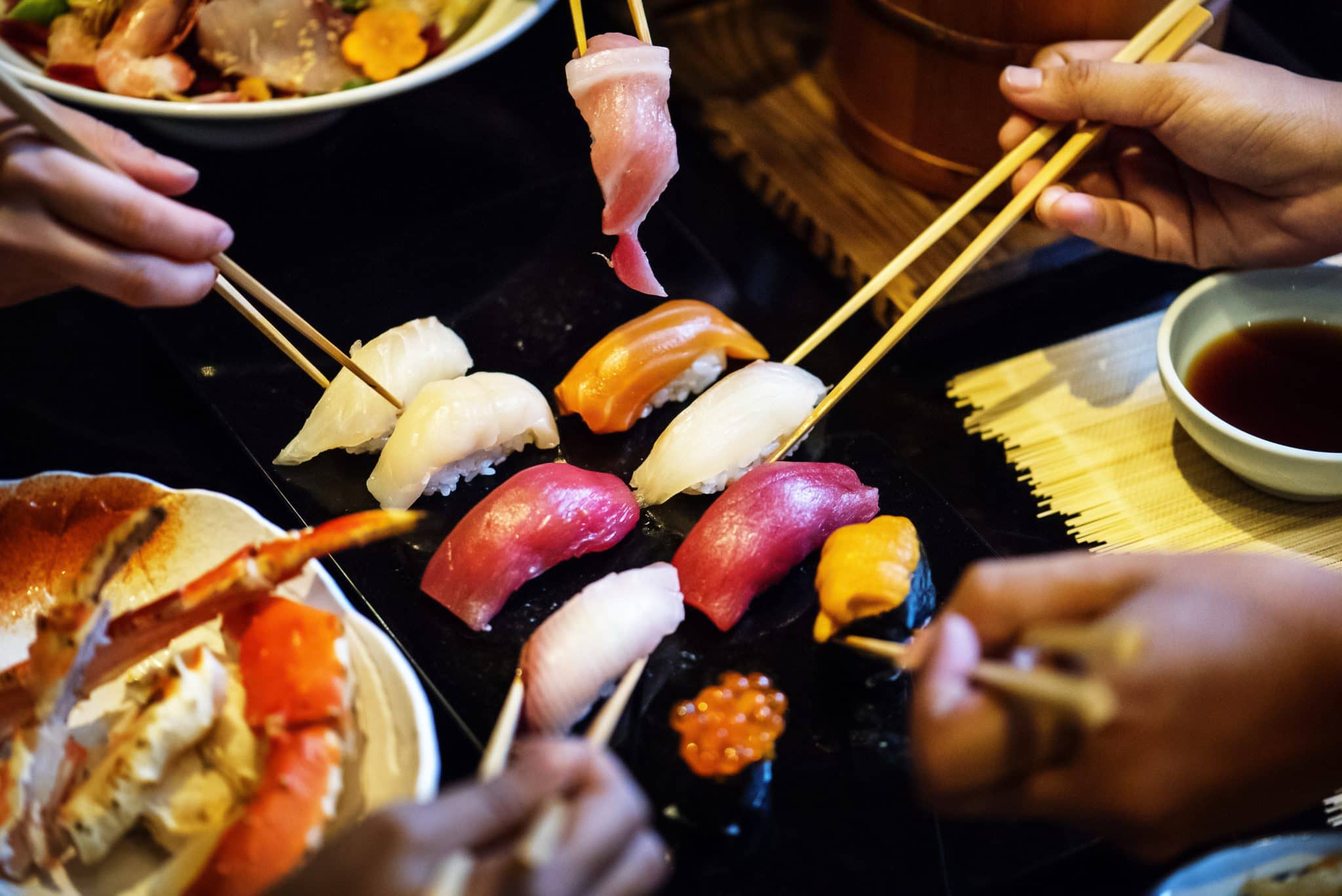Japanese seafood and sushi displayed on a table with chop sticks
