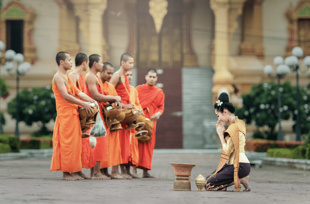 Thailand cultural heritage image with monks in traditional robes and woman praying